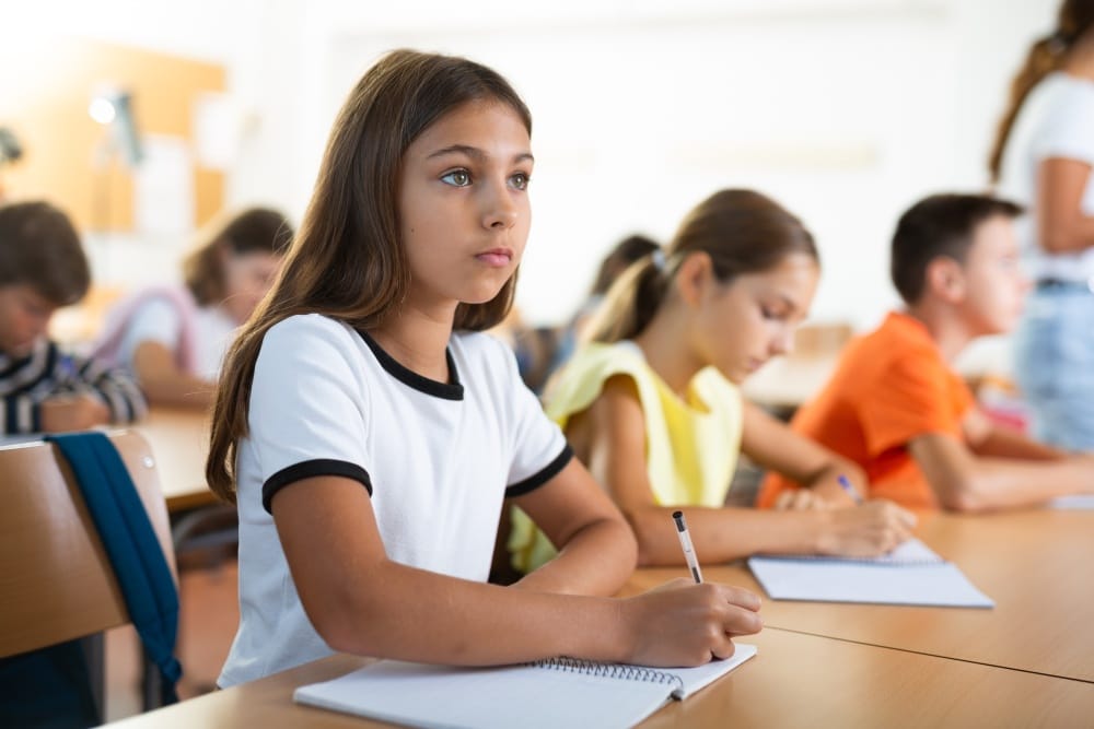 Estudiante escribiendo en un cuaderno durante una clase escolar